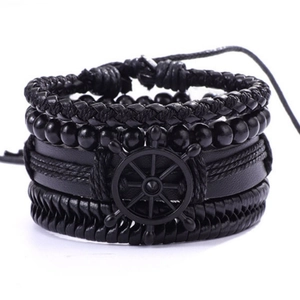 Gros plan d'un bracelet multicouche en cuir noir avec corde tressée et charme de gouvernail