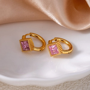 Detailed shot of gold star hoop earrings featuring square pink zircon in ceramic dish