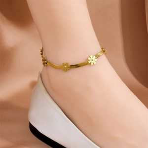 Detail of a gold titanium steel daisy flower blade chain anklet worn by a model