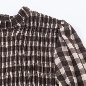 Detailed macro view of brown and white checkered blouse with elastic smocking patterns