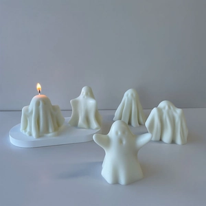 Detailed view of white ghost-shaped candles with one lit flame for Halloween decor