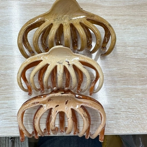 Close-up of three 13cm hand-painted large octopus hair claws in amber and beige tones