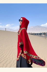 Close-up of red hooded poncho with ethnic embroidery in desert travel setting