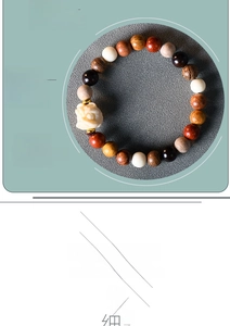 Dettaglio del bracciale in legni misti con un ciondolo Pixiu bianco intagliato