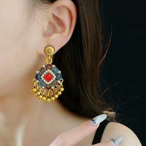 Gros plan de la boucle d'oreille vintage fleurie avec pierres rouges et pompon doré