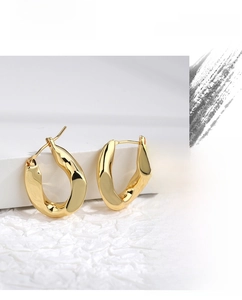 Detailed view of chunky golden U-shaped hoop earrings with polished metallic finish
