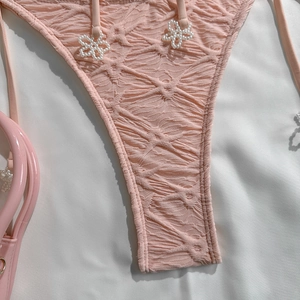 Close-up of pink textured bikini bottom with pearl flower detail and side ties