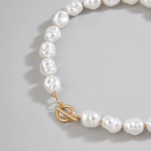Close-up of baroque pearl necklace featuring a golden OT toggle clasp detail