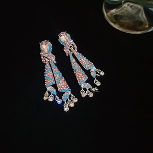 Detail of colorful tassel earrings with pink crystals and blue beads on black background