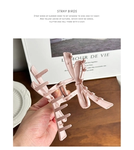 Close-up of large pink bow hair claw clip for elegant bun hairstyles on wooden background