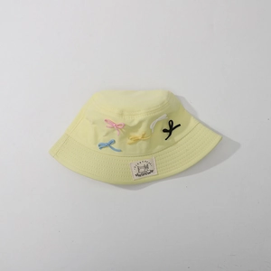 Detail of embroidered bows and brand label on a light yellow kids sun hat