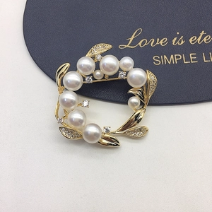 Elegant gold wreath brooch with white freshwater pearls and zircons on navy blue leather