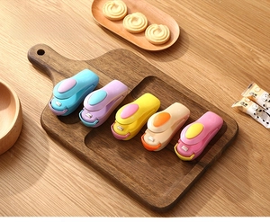 Tragbares Folienschweißgerät in fünf Macaron-Farben auf einem Holztisch mit Snacks