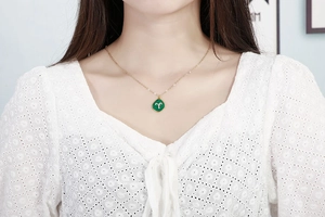 Close-up of Aries zodiac necklace featuring a green malachite pendant on model neck