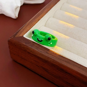 Close-up of a green cartoon frog open ring displayed in a wooden jewelry tray