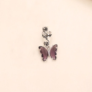 Macro detail of silver spiral dreadlock ring with a purple crystal butterfly pendant