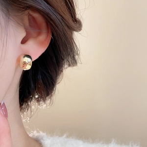 Close-up of elegant gold C-shaped drop earrings worn by a model for a classy look