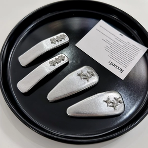 Detailed view of silver star hair clips in rectangular and teardrop shapes on black tray
