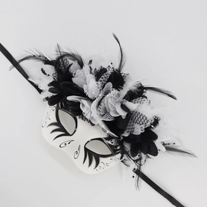Detailed shot of black and white masquerade mask with feathers, lace, and fabric flowers