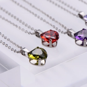 Three elegant heart-shaped zircon pendant necklaces in red, green, and purple with silver chains