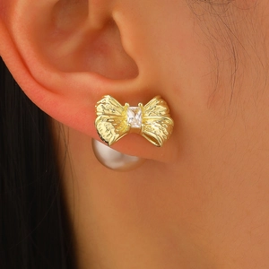Macro detail of gold bow earring with zircon stone and white pearl back on model