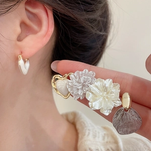 Detail view of heart-shaped hoop and floral stud earrings set with pearl accents