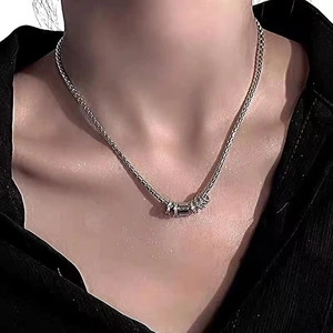 Close-up of minimalist silver circular pendant necklace worn on a black shirt collar