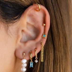 Macro view of gold stainless steel earrings with natural pearls and blue gemstones