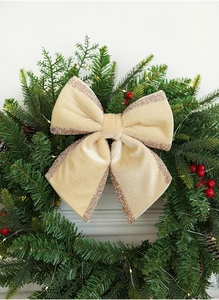 Velvet champagne Christmas bow with gold glitter edge on green festive wreath decor