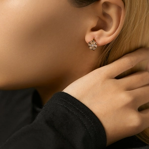 Close-up of elegant rose gold snowflake stud earrings with sparkling cubic zirconia on model