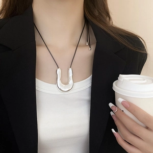 Detail of silver shell pendant on black cord worn with a blazer and white top