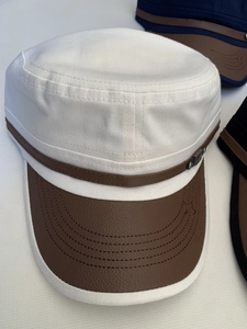 Detailed view of white canvas cadet hat with brown leather brim and star embroidery
