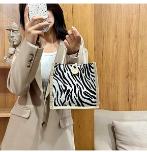 Detail of zebra pattern canvas tote with rustic wooden button and braided handles