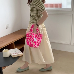 Chic pink leopard print canvas tote bag carried by a model in a stylish indoor setting