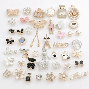 Macro shot of pearl chains, rhinestone bow, and enamel charms for DIY shoe decoration
