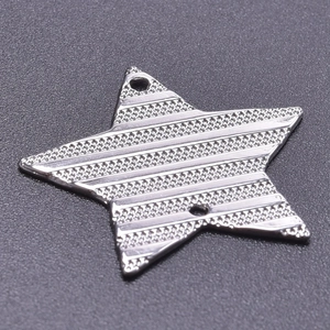 Macro detail of star shaped stainless steel pendant with striped texture and dual holes