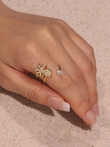 Detailed view of a golden octopus open ring with cubic zirconia stones on a sandy beach