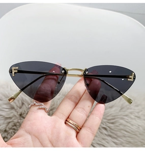 Close-up of frameless cat eye sunglasses with metal temples and rhinestone F detail