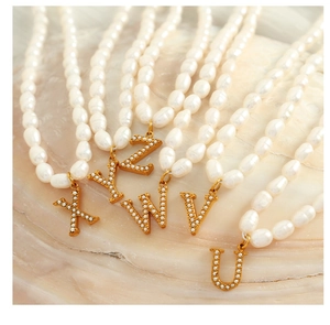 Detail of gold letter pendants with micro-pearls on a white freshwater pearl necklace