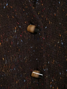 Macro shot of brown mixed-color knit fabric texture with horn-style button detail