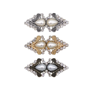 Three elegant rhinestone sweater clips in silver, gold, and dark grey with pearl detail