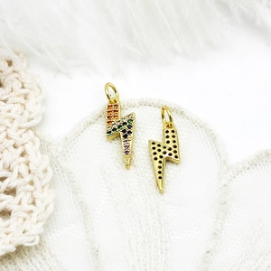 Detailed view of lightning pendants with colorful and black stones on white lace and feather