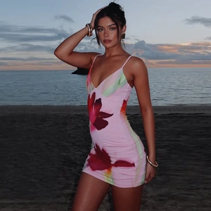 Floral print pink bodycon dress with backless design shown on a beach at sunset