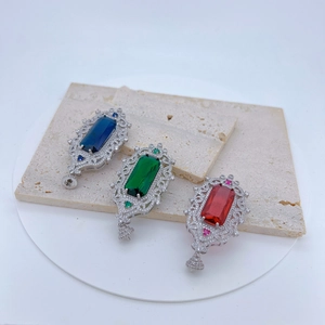 Macro detail of Baroque style pendants with emerald, sapphire, and ruby crystals