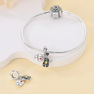 Detailed view of silver snake chain bracelet with guitar wing and heart music charms