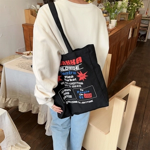 Detailed view of black canvas tote bag featuring vintage graphic prints and wide shoulder straps