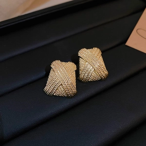 Macro shot of gold square earrings with woven texture and X-design in a black jewelry box