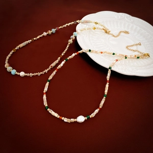 Detail of colorful beads, irregular pearls, and gold metal hardware on necklaces