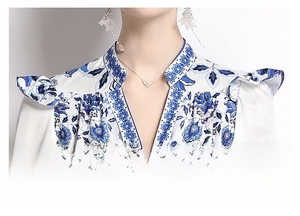Detail of V-neckline with delicate ruffles and blue floral print on white chiffon dress