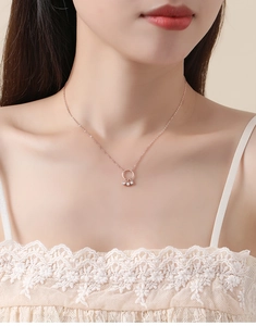 Detail of rose gold dreamcatcher necklace with sparkling zircon pendants on model